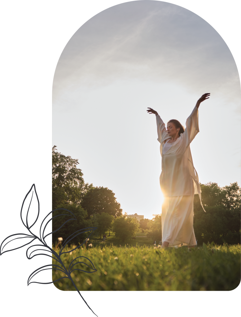 A woman in a flowing white outfit stands on grass with arms raised, basking in sunlight like a spiritual director embracing serenity, in a park surrounded by trees. The image features a soft arch frame and a simple line drawing of leaves on the left side.